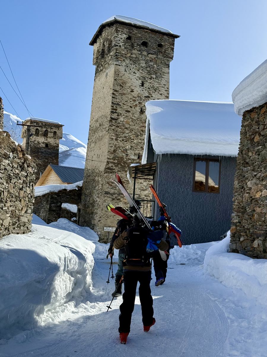 Enric caminant amb els esquís a l'esquena entre les torres de pedra d'un poble de Svaneti